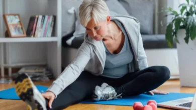 mature woman exercising at home learning exercises online with laptop