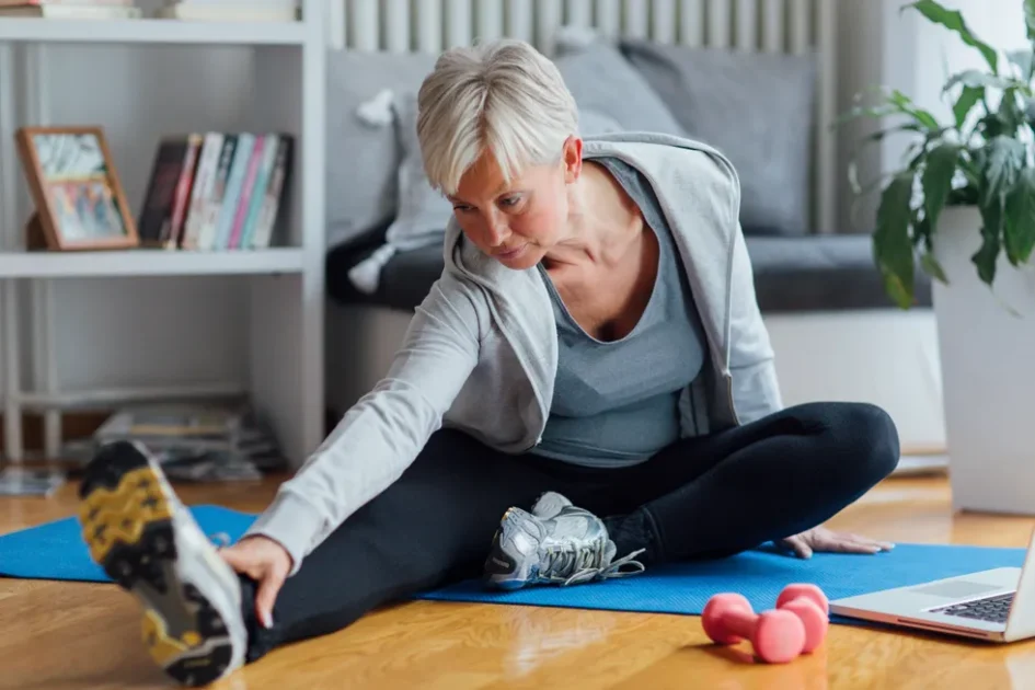 mature woman exercising at home learning exercises online with laptop